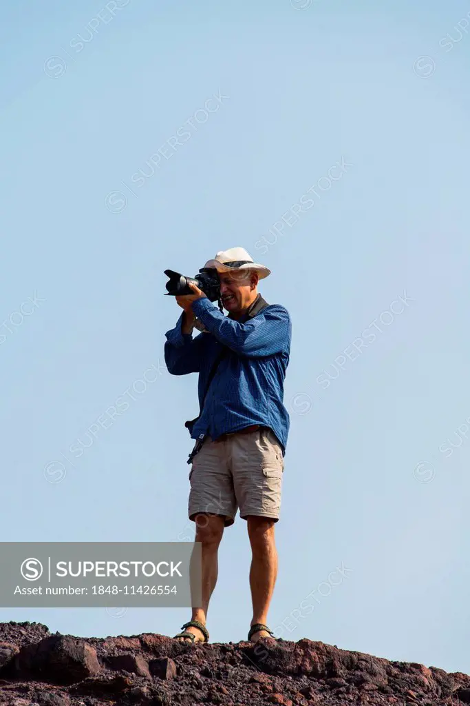 Man taking a photo standing on a rock, Namibia
