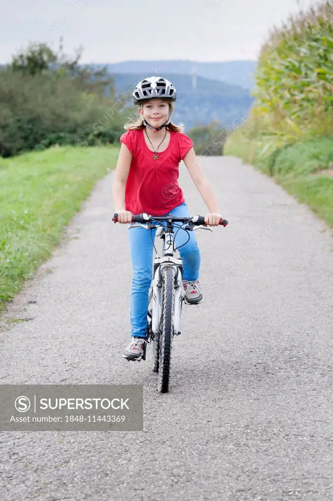 Girl, 9 years, riding a bicycle wearing a helmet
