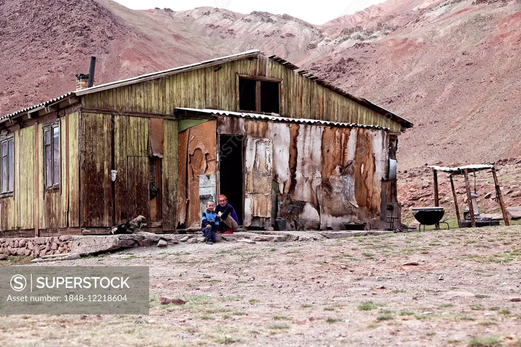 People sitting outside a delapidated hut, settlement on the Pamir Highway, M41, Province of Gorno-Badakhshan, Tajikistan