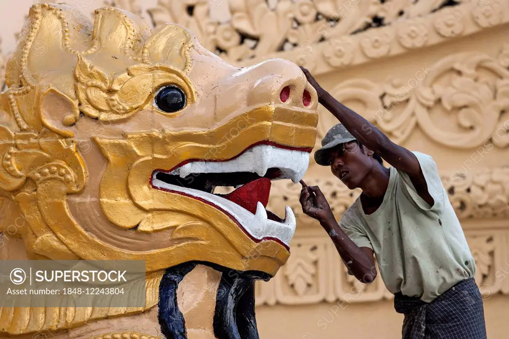 Man carrying out restorations, golden lion's head, Maha Wizaya Pagoda, Yangon, Myanmar