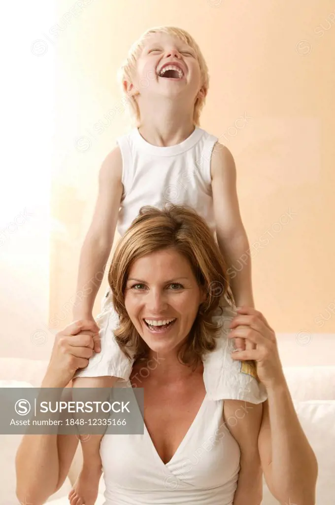 Little boy sits on his mother's shoulders