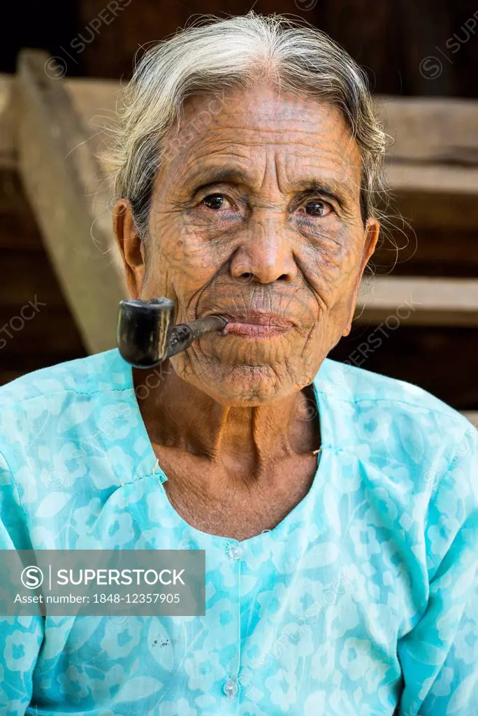 Woman of the Chin people, ethnic minority, with a traditional facial tattoo smoking a pipe, the last of their kind, portrait, Rakhine State, Myanmar