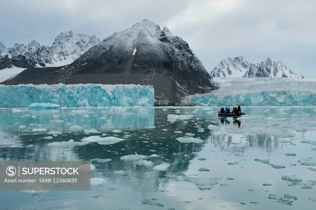 Tourists in a rubber dinghy in front of the rim of the Monacobreen Glacier, Liefdefjorden, Spitsbergen, Svalbard Islands, Svalbard and Jan Mayen, Norw...