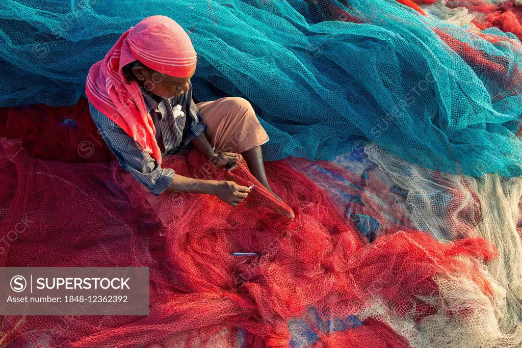 Fisherman repairing fishing nets, Varkala, Kerala, India