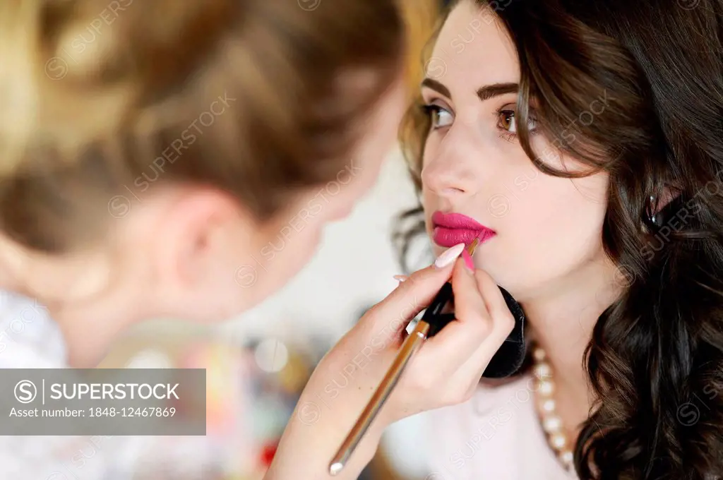 Young woman having make-up done by make-up artist