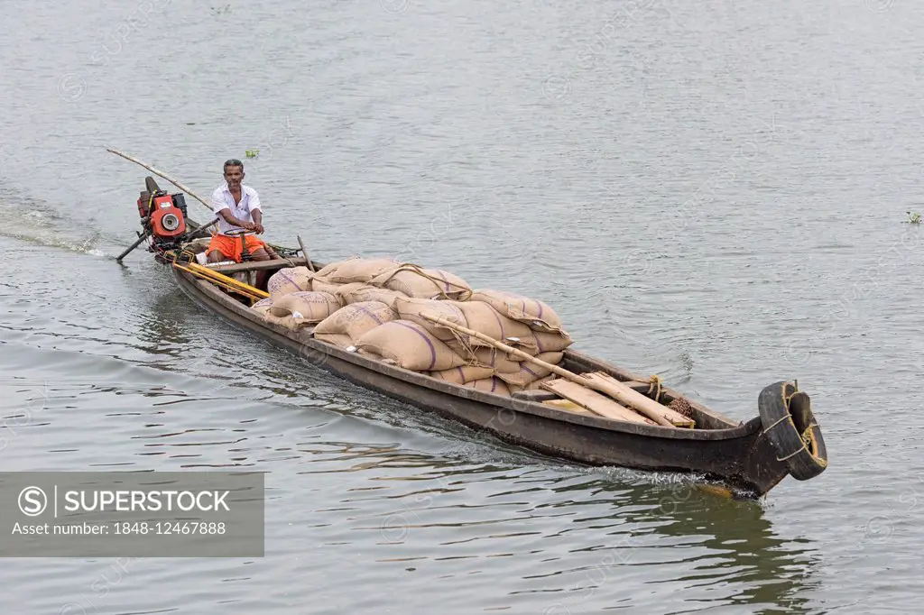 Man steering a boat laden with sacks, canal system Backwaters in Alappuzha, Kerala, India
