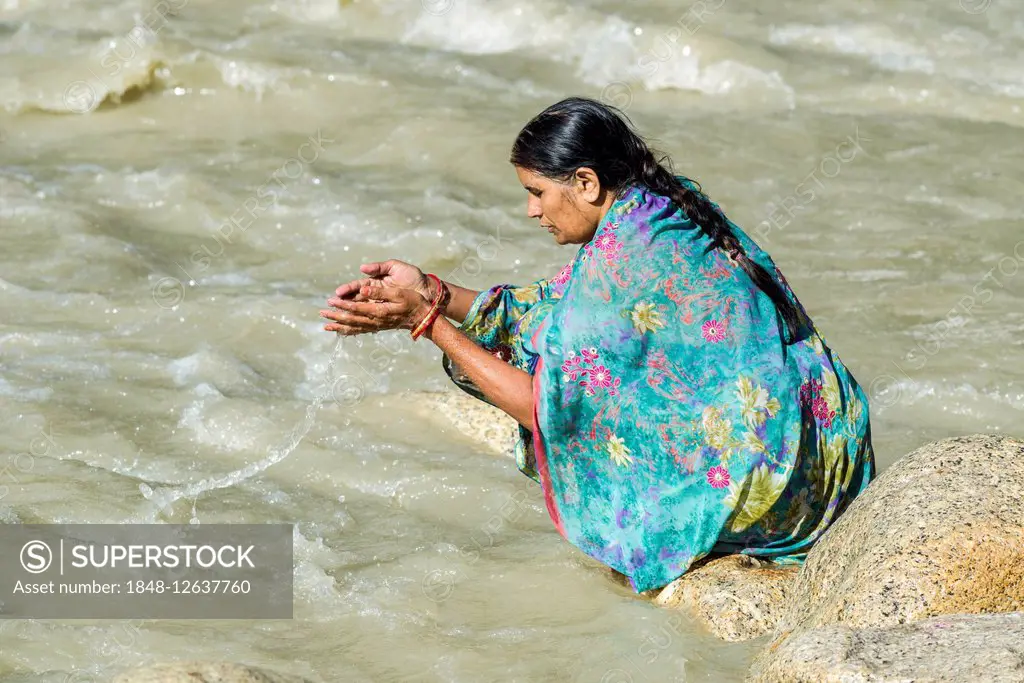 A female pilgrim at the banks of the river Ganges is praying, offering the holy water, Gangotri, Uttarakhand, India