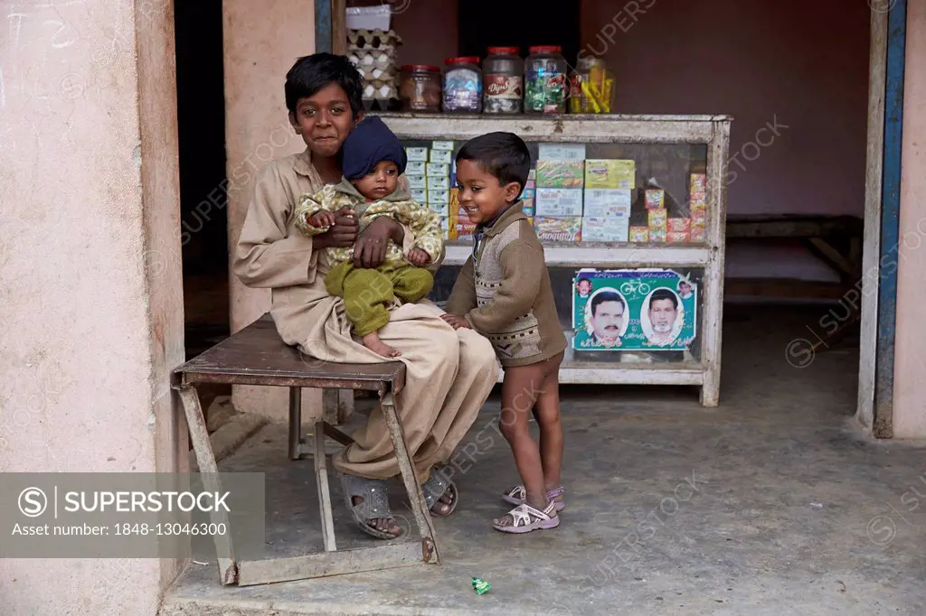 Children sitting in front of a small shop, Mahey, Pakistan