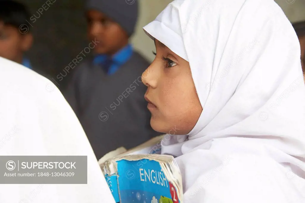 Girl with a book learning english in a primary school, Mahey, Pakistan