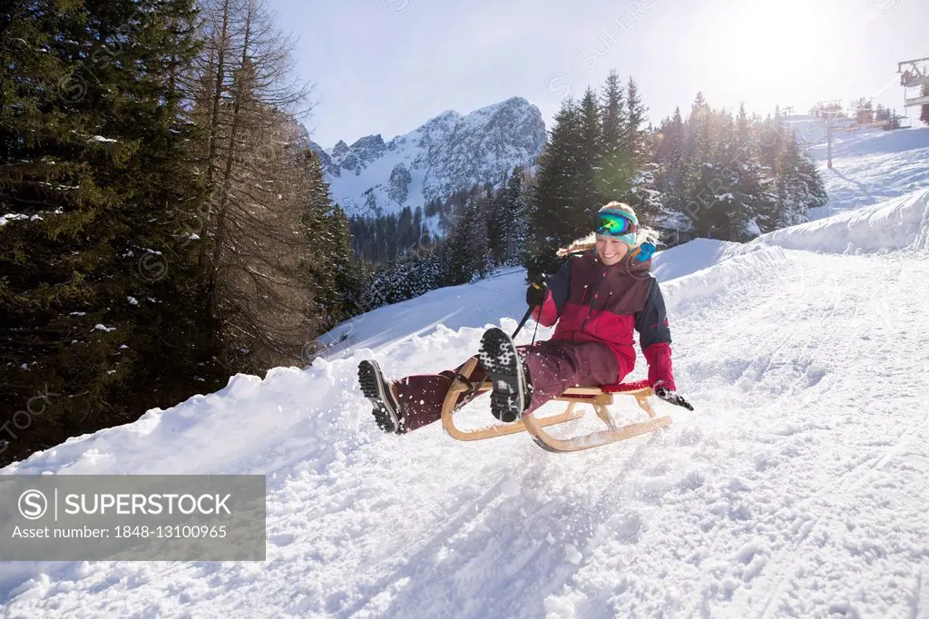 Young woman riding on a sledge, making a jump, Muttereralm Innsbruck, Tyrol, Austria