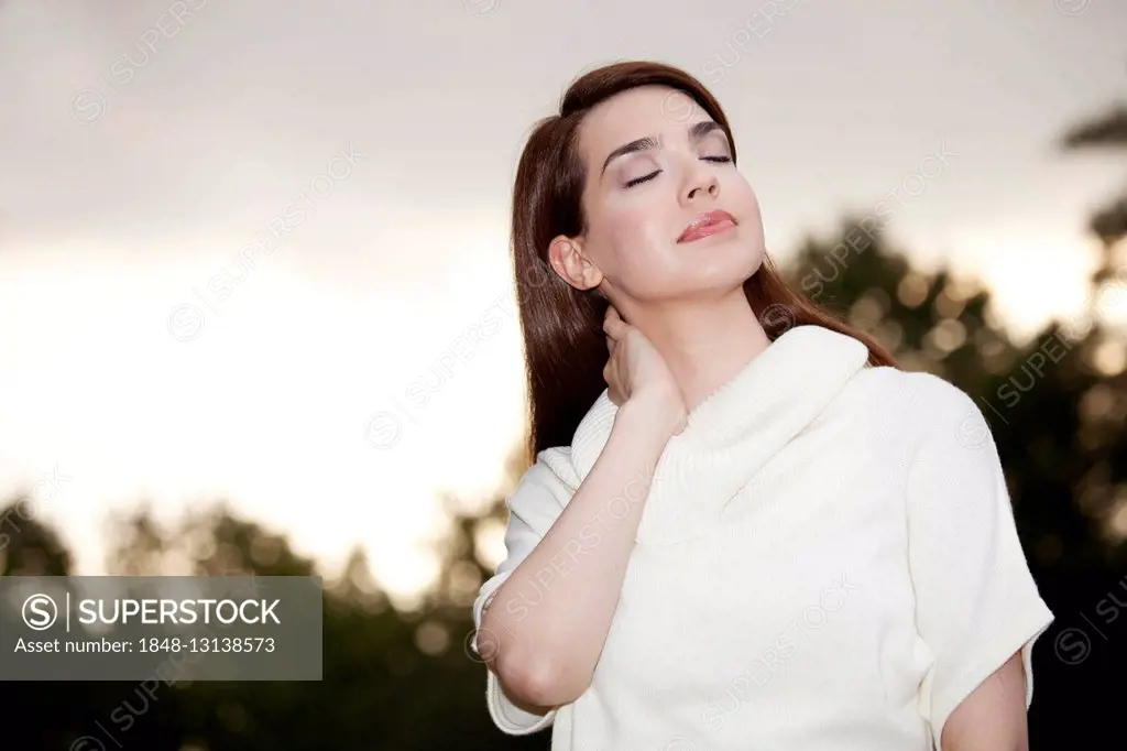 Young woman with closed eyes enjoying the summer evening mood