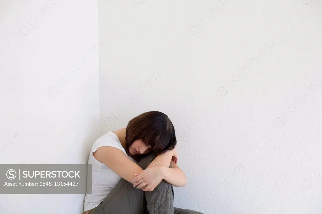 Sad young woman sitting in a corner