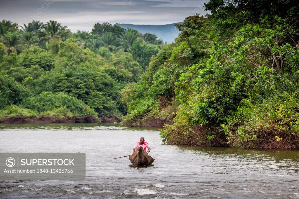 Man in dugout canoe, navigating river, Foumbam, West Region, Cameroon, Africa