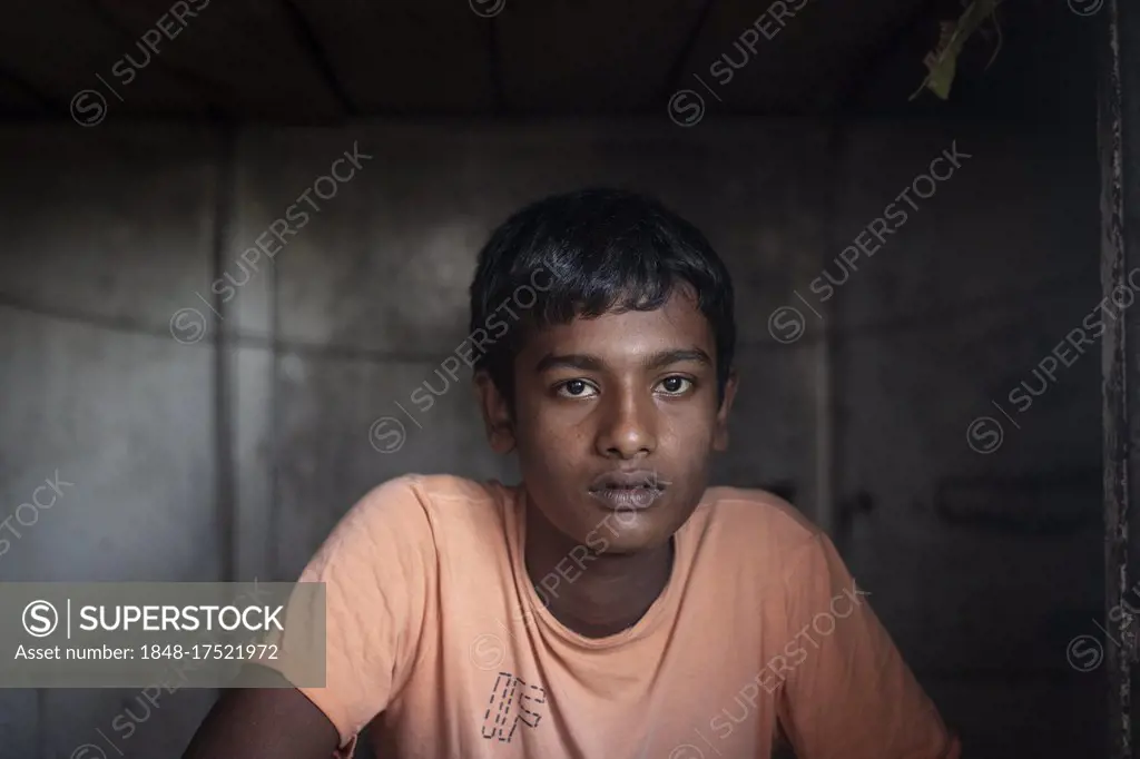 A sailor is sitting at the entrance of his sleeping cabin on a freighter in the port of Mongla, Sundarbans, Bangladesh, Asia