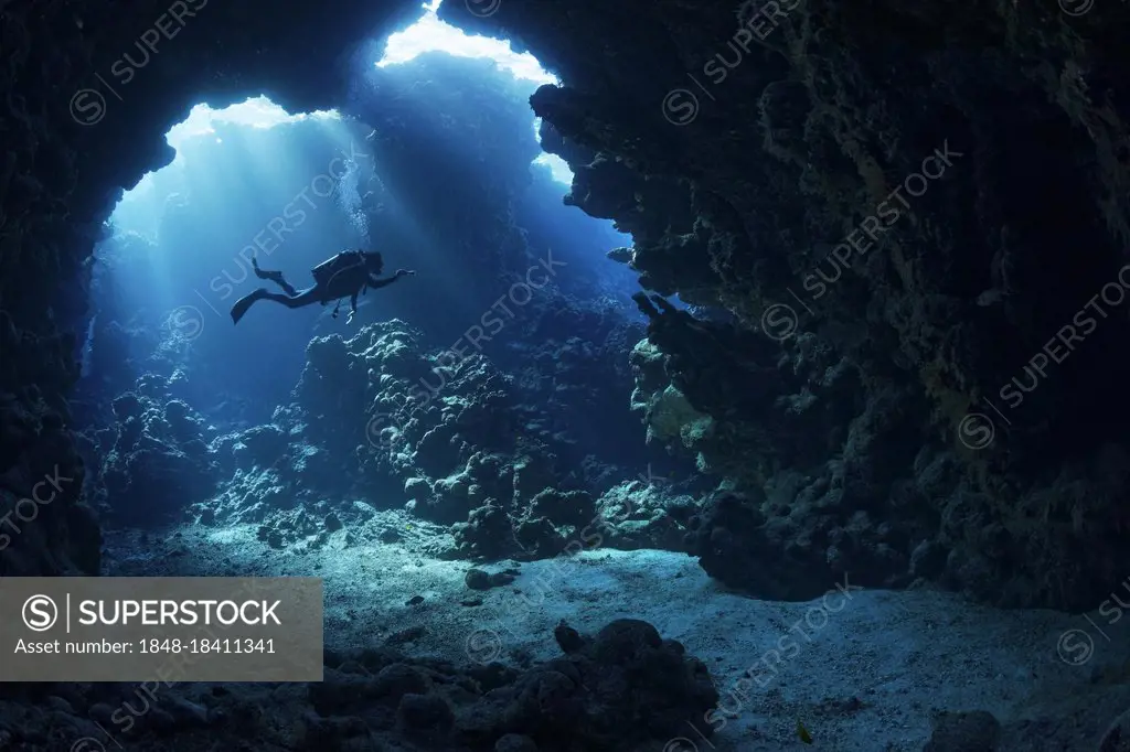Sunbeams shining through reef top in cave in coral reef with diver, Shaab Claude, Red Sea, Fury Shoals, Egypt, Africa