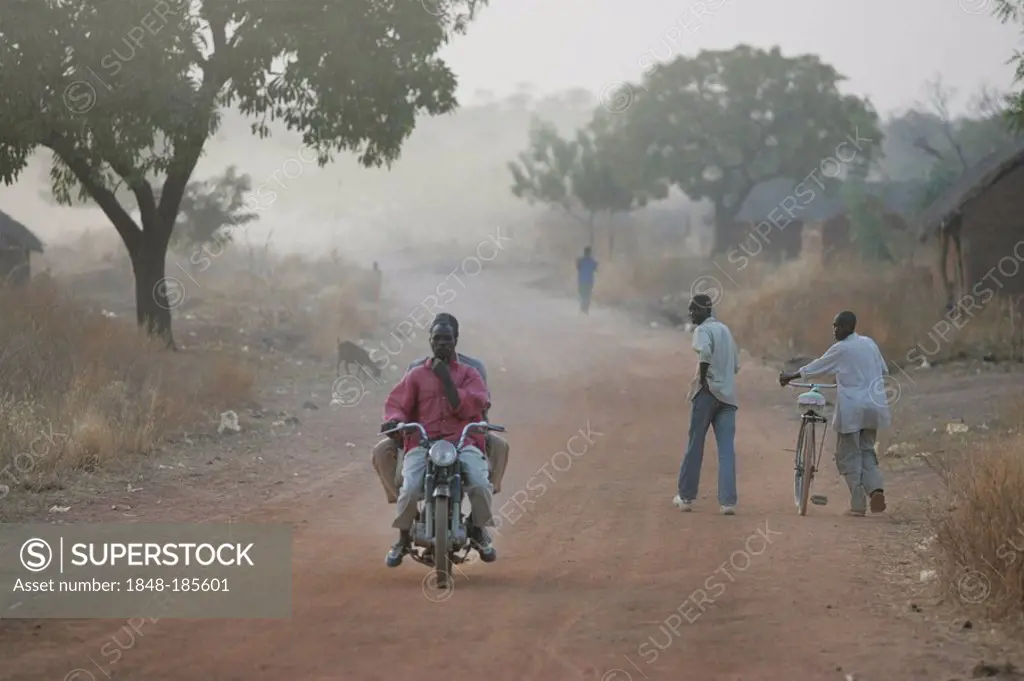 Men with a bike and a man riding a motorbike, at dawn, Houssere Faourou, Cameroon, Africa