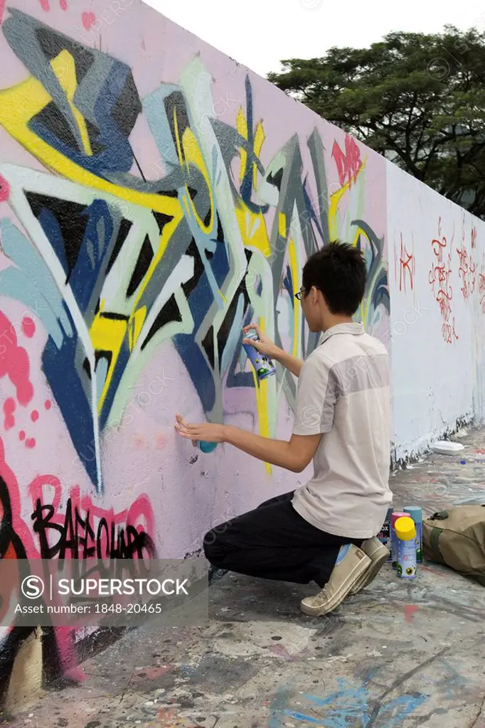 Boy spraying graffiti on a wall in Singapore, Southeast Asia