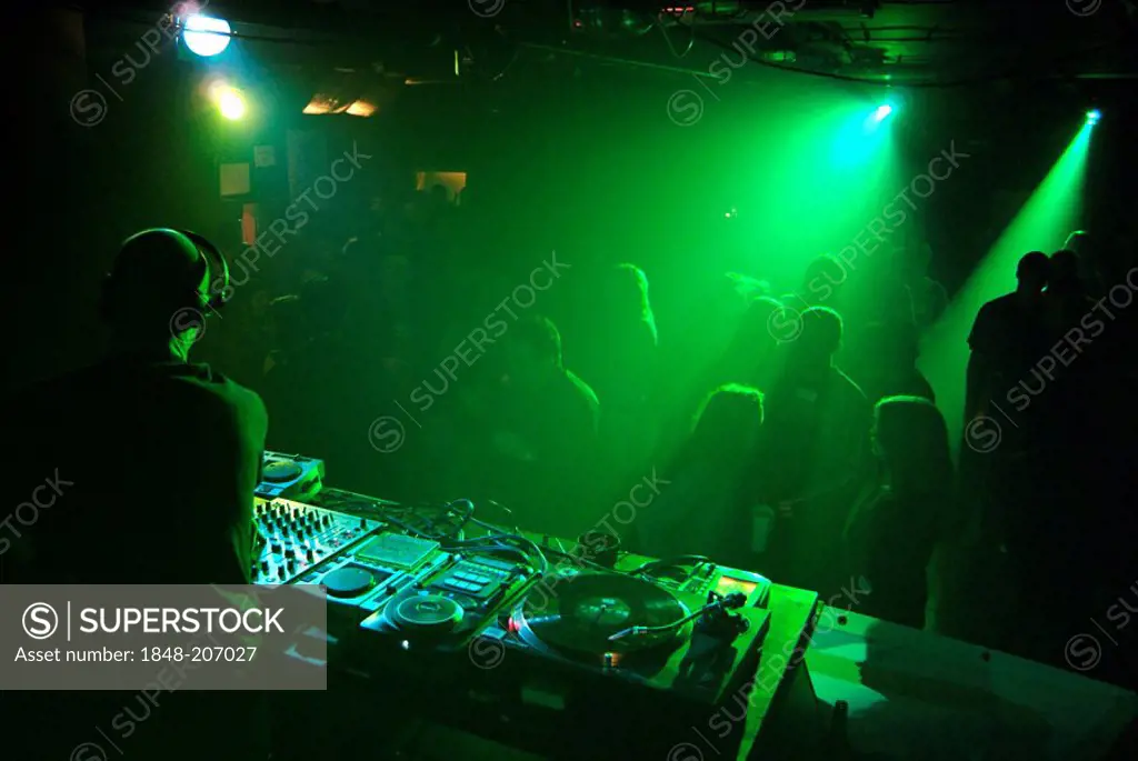 Club DJ playing a set in a crowded nightclub