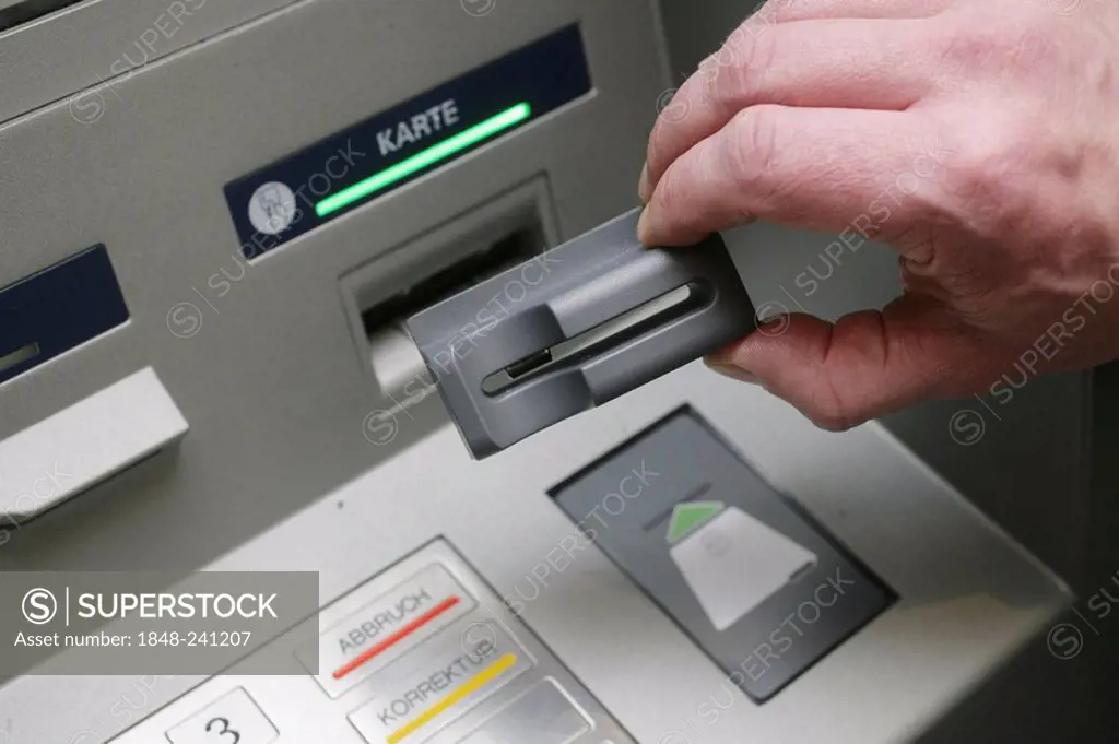 Bank employee demonstrating technical devices used by criminals to spy out numbers and pin codes of bank cards at an ATM machine