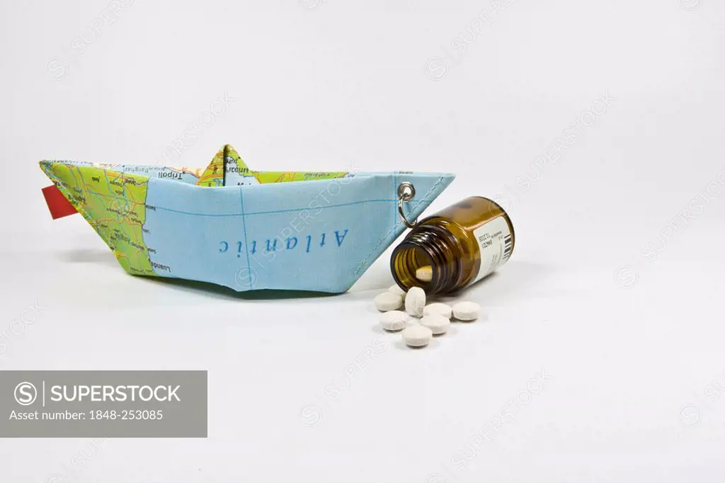 Pills and a paper ship made from a map: symbol for anti-seasickness medication