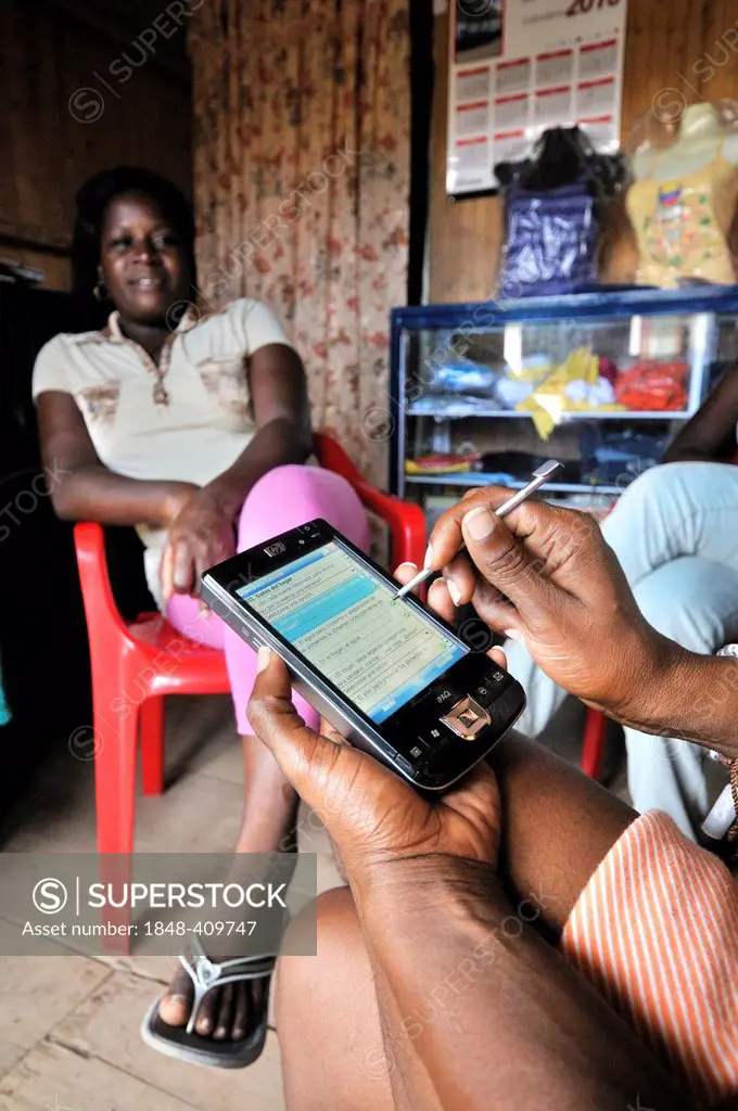 Social worker collecting data about the living situation of a poor Afro-Colombian family with a smartphone, Bajamar slum, Buenaventura, Valle del Cauc...