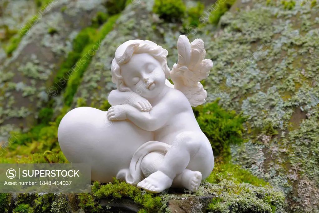 Angel figurine made of clay on mossy stones