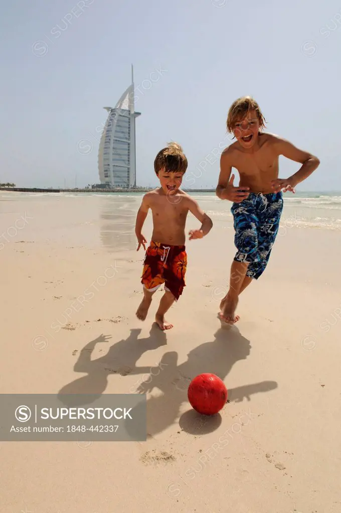 Children playing soccer on the beach in front of the Burj al Arab Hotel, Dubai, United Arab Emirates, Middle East