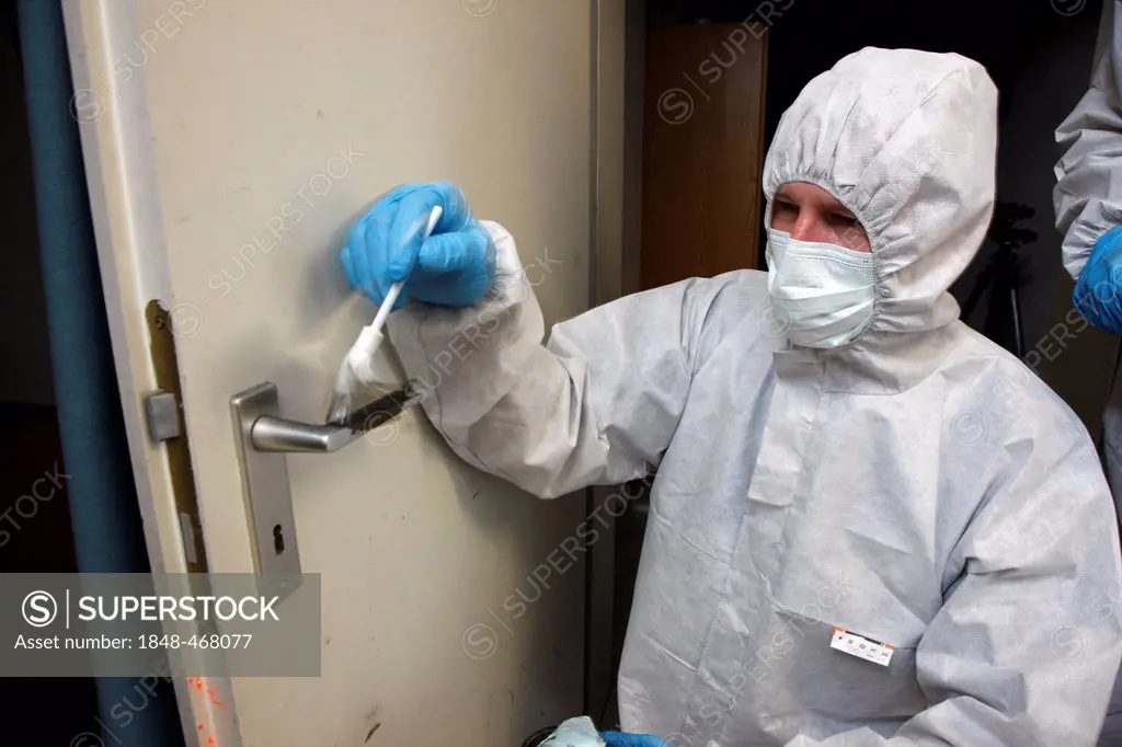 Fingerprints are being made visible with charcoal powder and secured on adhesive film, officer of the C.I.D., the Criminal Investigation Department, g...