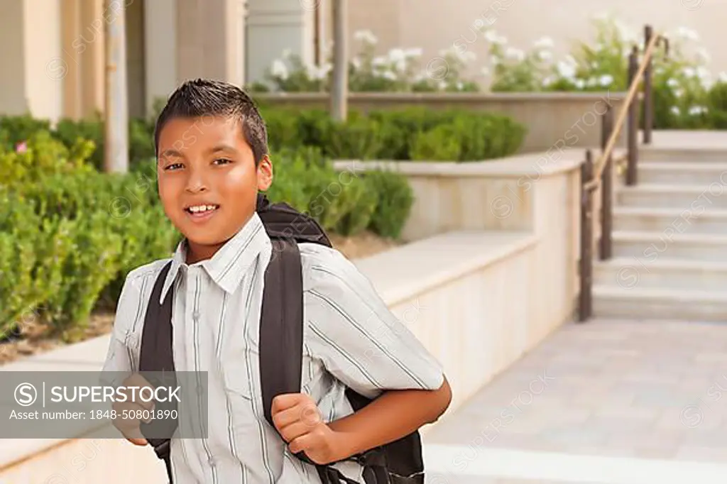 Happy hispanic boy with backpack walking on school campus