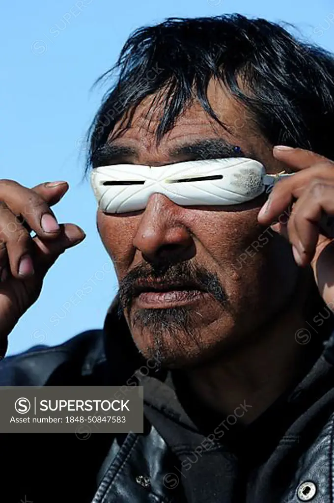 Portrait of Inuit man with traditionnal sunglasses made of whale bone, Igloolik, Foxe Basin, Nunavut, Canada, North America