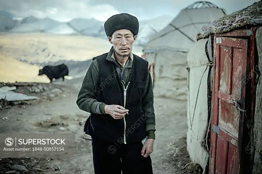 Portrait village headman, Kyrgyz nomadic settlement, behind him a yak, a yurt and the snow-covered peaks of the Hindu Kush, Khadz Goz, Wakhan Corridor, Badakhshan, Afghanistan, Asia