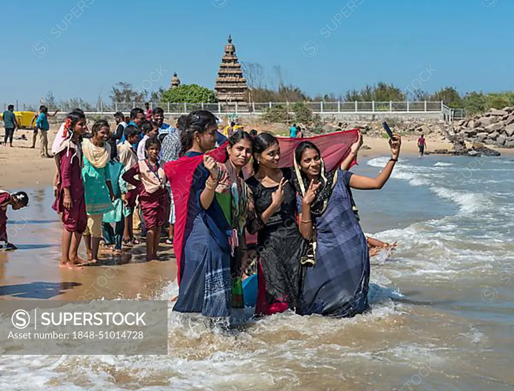 Teenage girls take selfie on the beach in front of Shore Temple, Mahabalipuram, Mamallapuram, India, Asia
