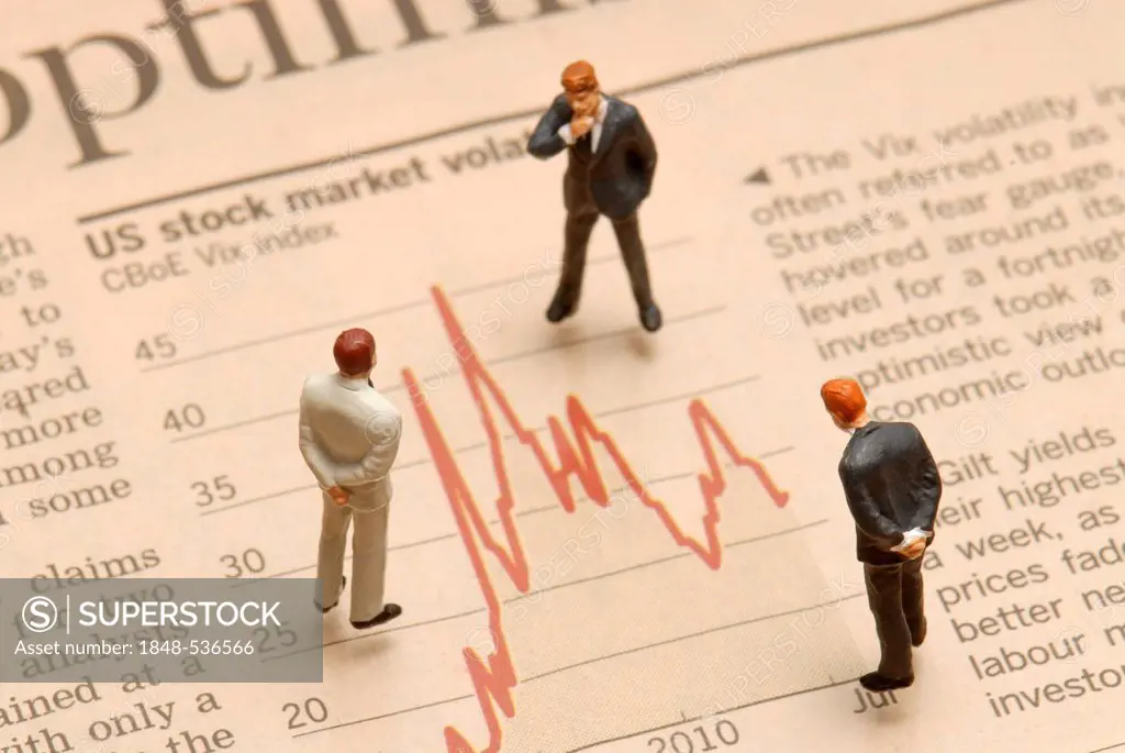 Miniature businessmen figures standing on a stock market chart