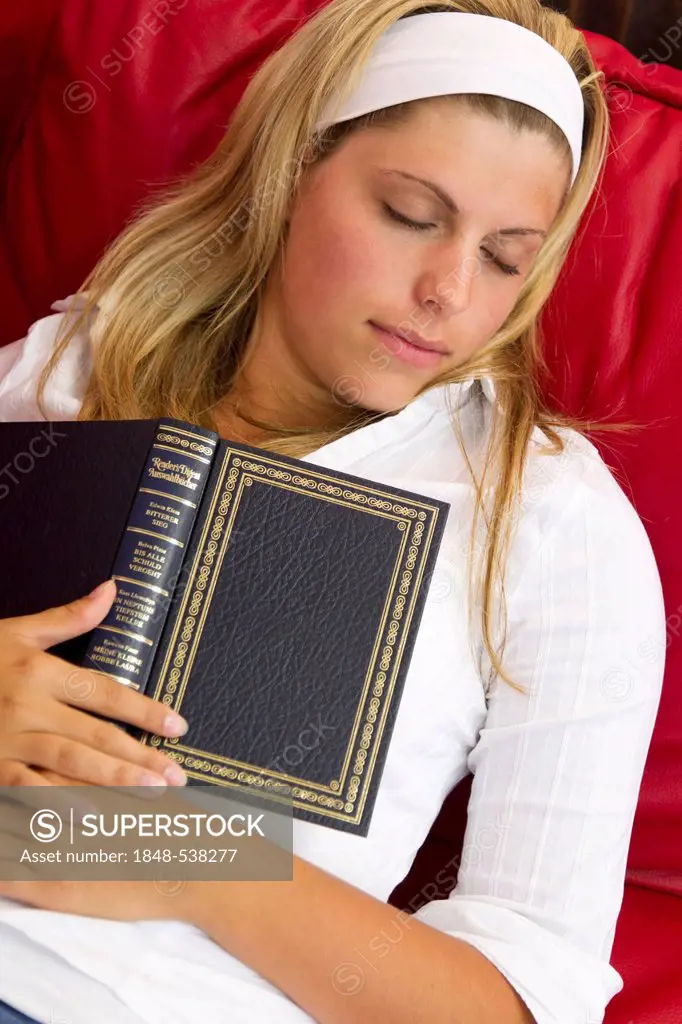 Young woman fallen asleep while reading on a sofa