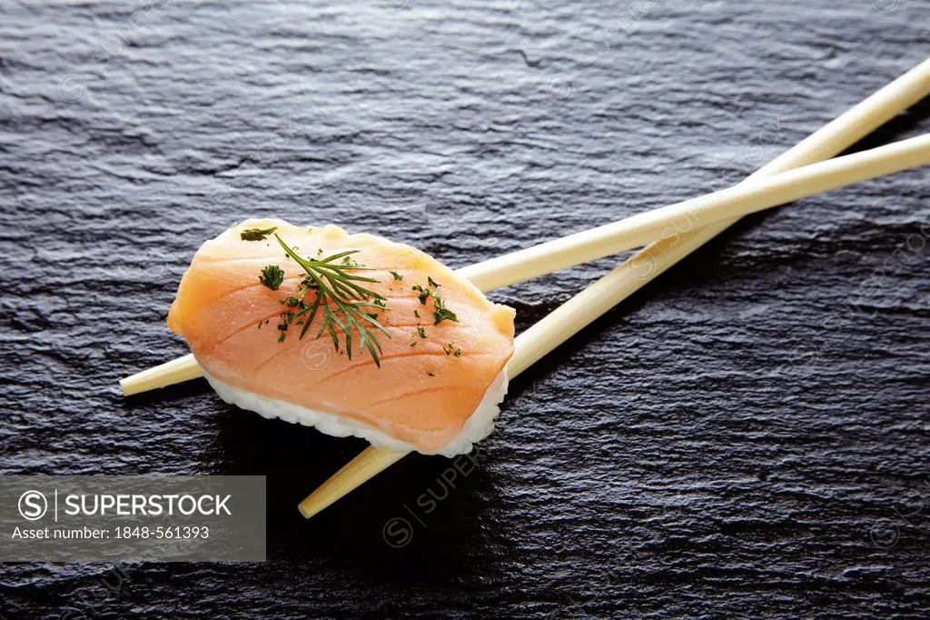 Sushi, nigiri with salmon and chopsticks on a slate surface