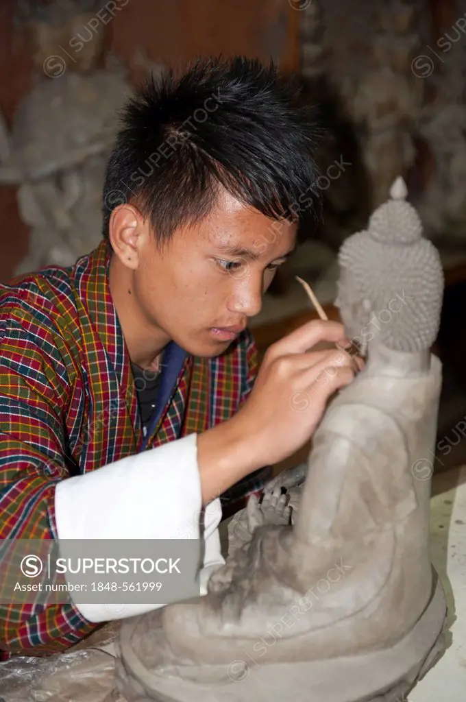 Young man training to become a sculptor, working very focused on a small Buddha statue, handicraft, National Institute of Zorig Chusum, Painting Schoo...