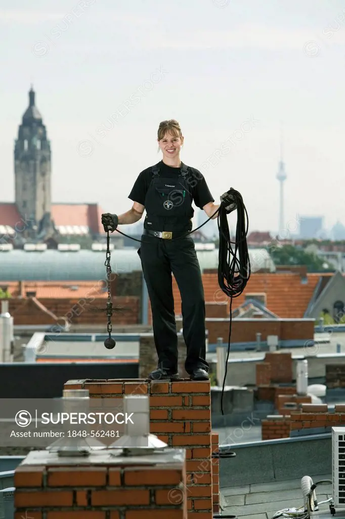 Chimney champion Steffi Marienfeld at work on the roof of a house in Charlottenburg, with the Berlin Television Tower on the horizon, Berlin, Germany,...