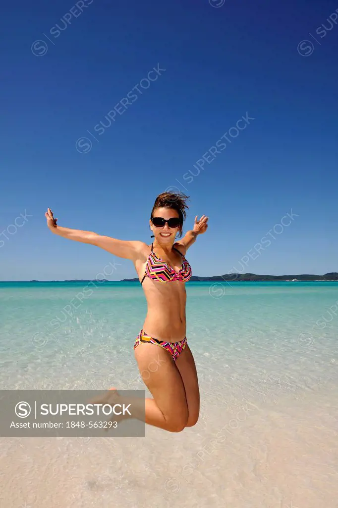 Young woman cutting a caper by the sea, symbolic for enjoying life, Whitehaven Beach, Whitsunday Island, Whitsunday Islands National Park, Queensland,...