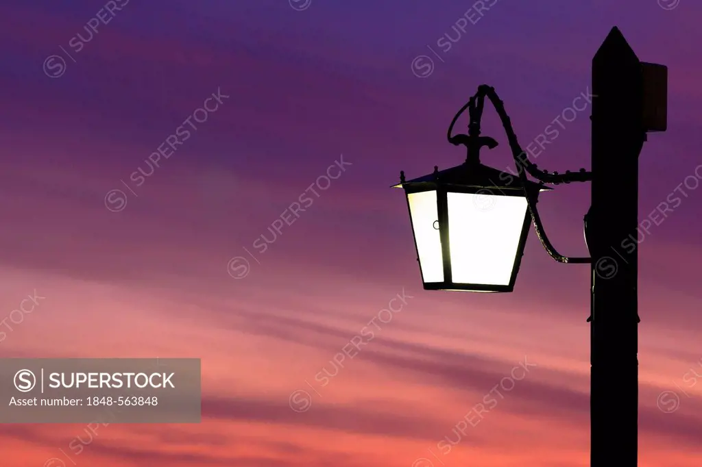 Street lamp silhouetted against the setting sun in Venice, Italy, Europe