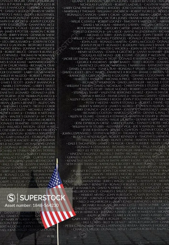 US flag in front of the Vietnam Veterans Memorial Wall, national memorial with the names of fallen US soldiers during the Vietnam War, Washington DC, ...