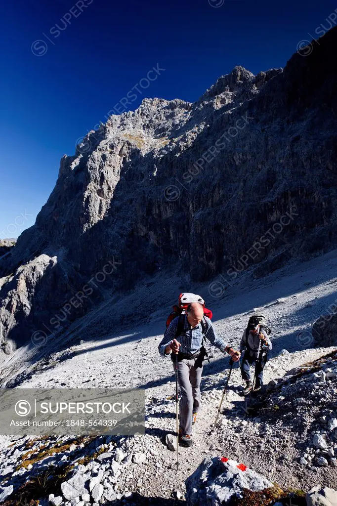 Hikers in Elferscharte during the ascent to the Alpinisteig fixed rope route across Fischleintal valley above Talschlusshuette mountain hut, Hochpuste...