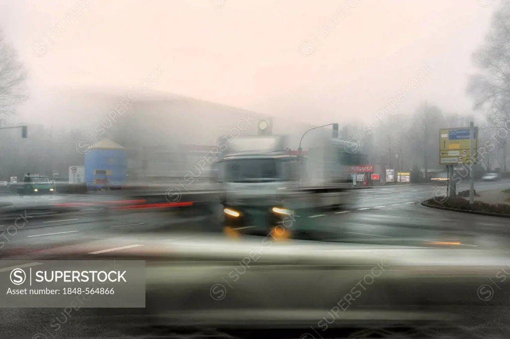 Trucks and cars at an intersection in the morning mist, motion blur