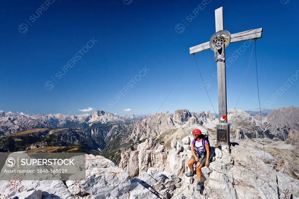 Hiker at the summit cross of Mt Paternkofel or Paterno, Mt Schwalbenkofel and Mt Hohe Gaisl or Croda Rossa in the back, Rienza valley below, Sexten, S...