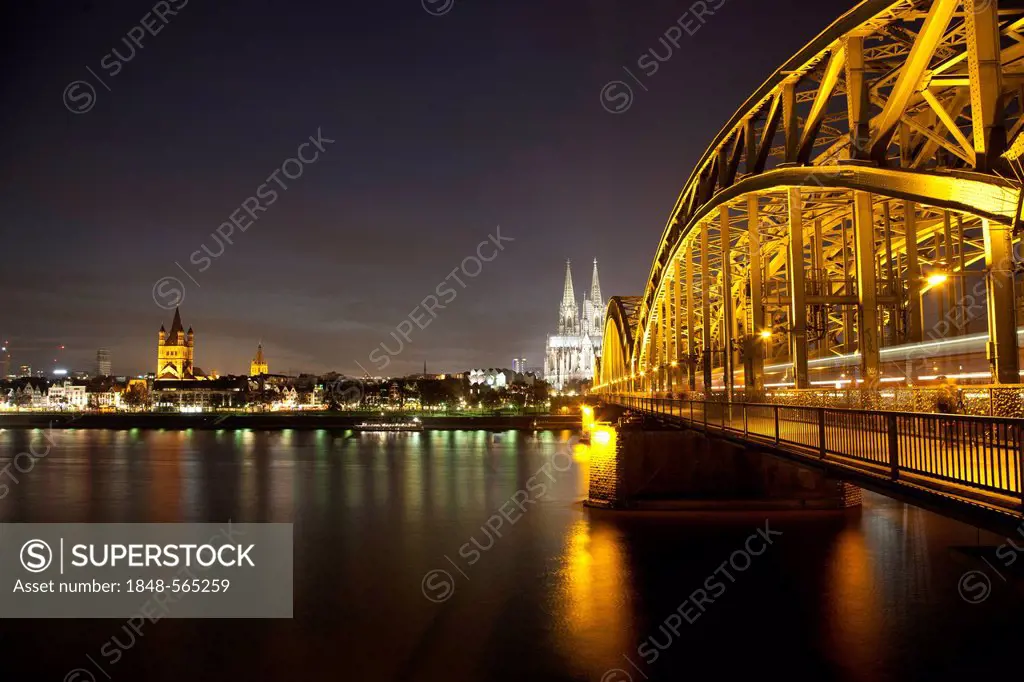 Illuminated Hohenzollern Bridge over the Rhine with the bank of the Rhine, Cologne Cathedral and Gross St. Martin church, Cologne, Rhineland, North Rh...
