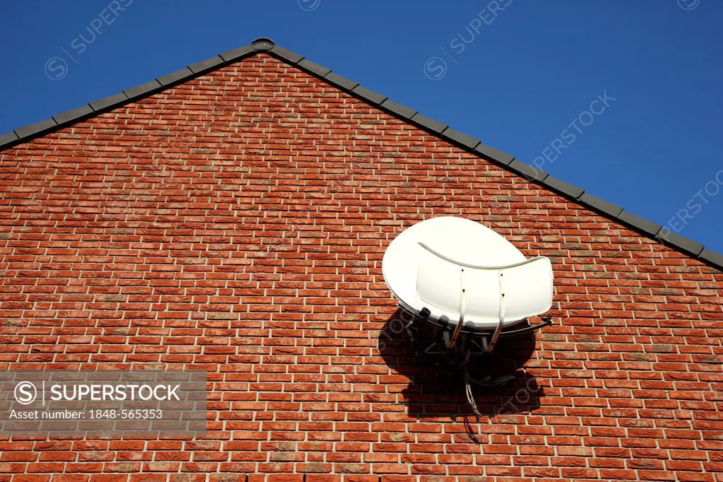 TV satellite dish with amplifier on the brick wall of a house, Duisburg, North Rhine-Westphalia, Germany, Europe