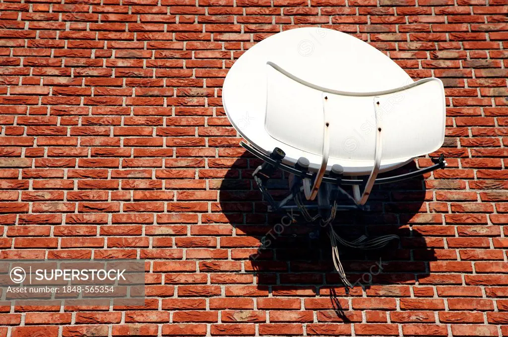 TV satellite dish with amplifier on the brick wall of a house, Duisburg, North Rhine-Westphalia, Germany, Europe