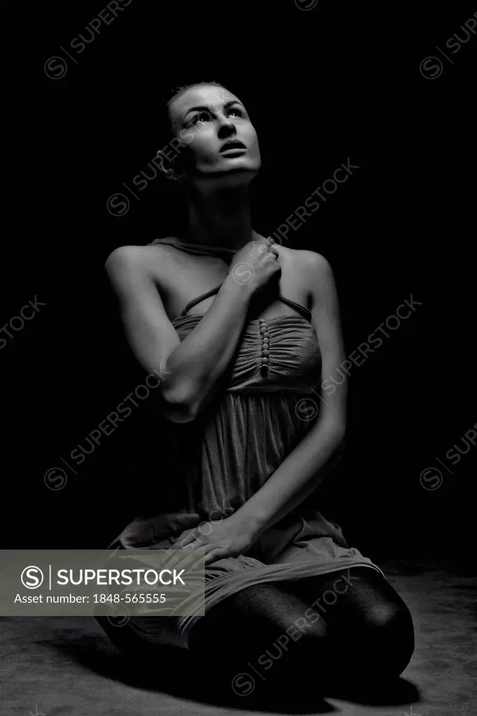 Young woman kneeling and looking upwards towards the light