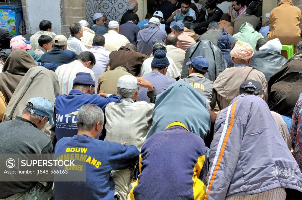 Men sitting in a street in front of a crowded mosque during Friday prayers, Essaouira, Morocco, Africa, PublicGround