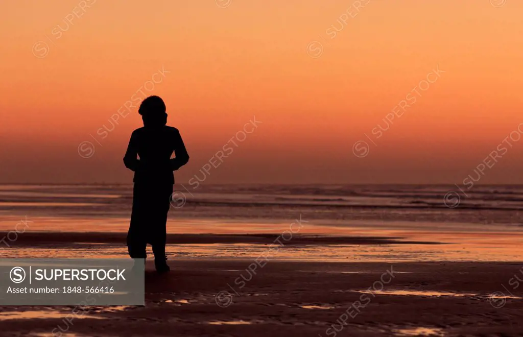 Silhouette of a woman on the beach looking into the sunset, Essaouira, Morocco, Africa