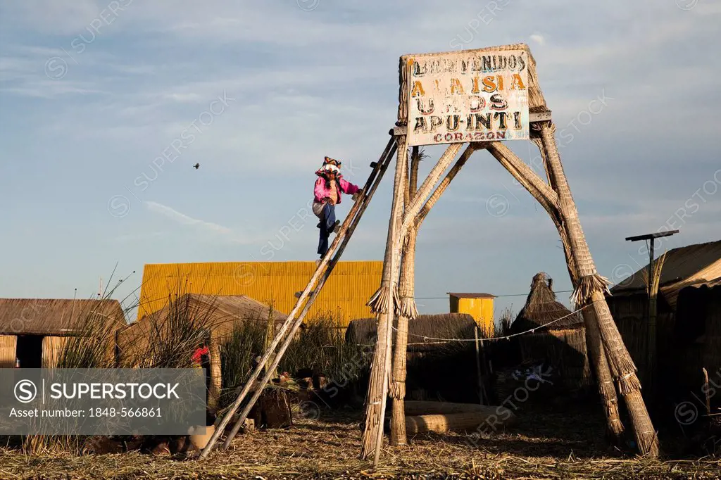 Girl climbing a lookout tower on the floating islands of the Urus on Lake Titicaca, constructed by the totora reeds growing there, Puno, Peru, South A...